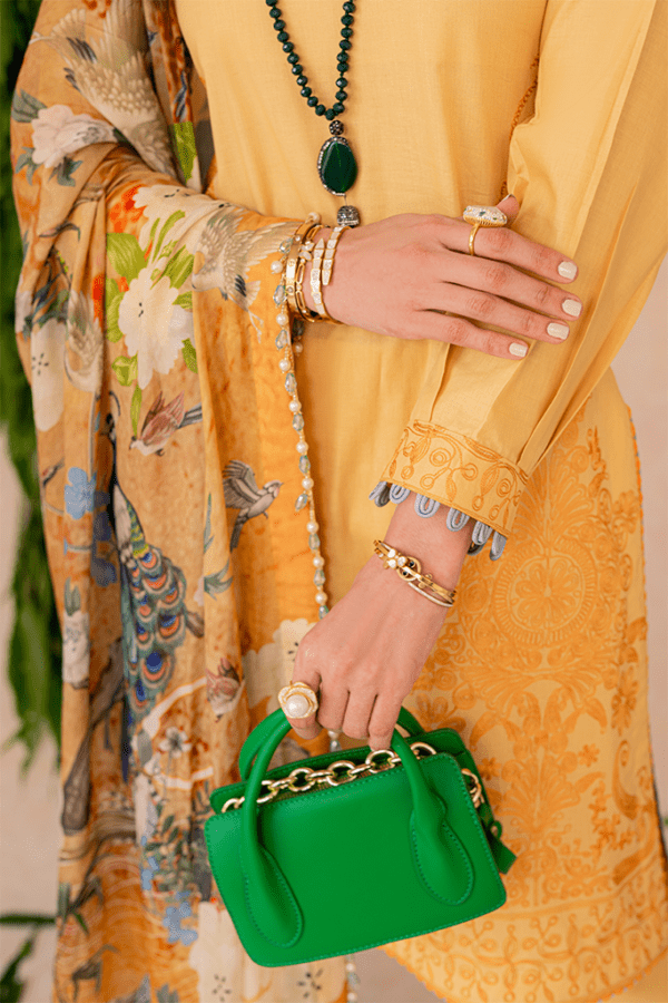 a woman in a yellow dress holding a green purse.